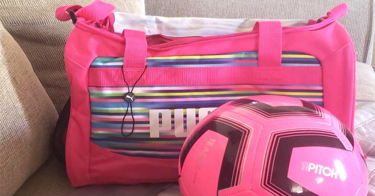 pink Puma duffel bag on a couch with a pink soccer ball