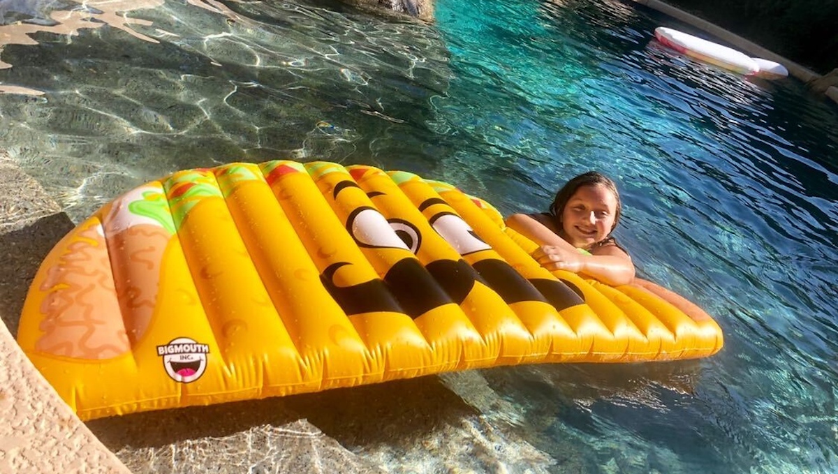 girl resting on taco pool float in water