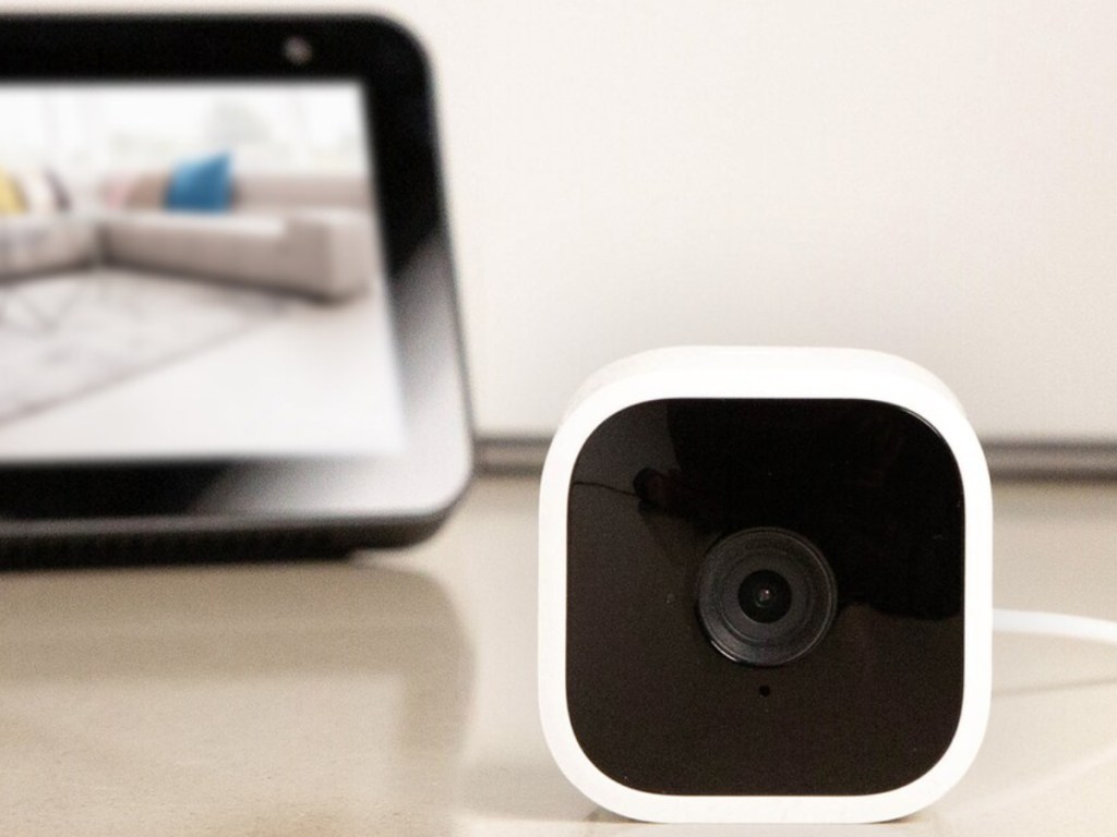 white security camera and black tablet on table in home