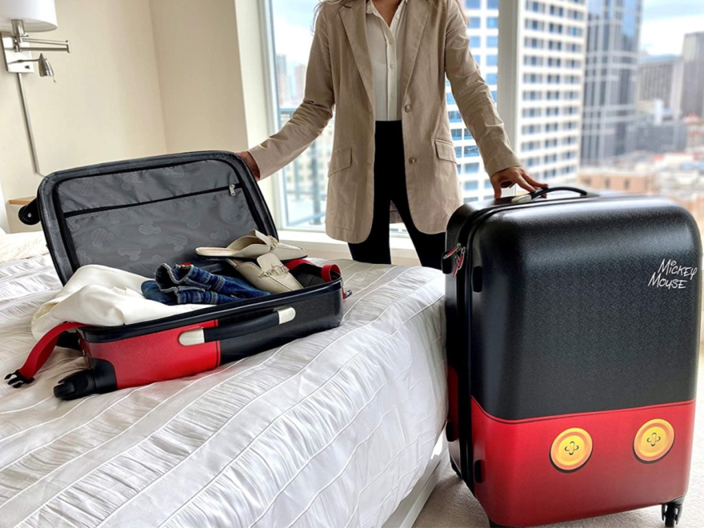 woman in hotel room with Disney themed luggage on bed