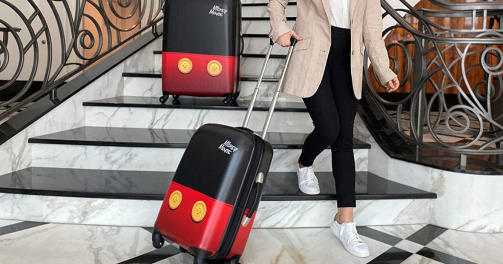 woman walking down large set of steps with Disney themed luggage