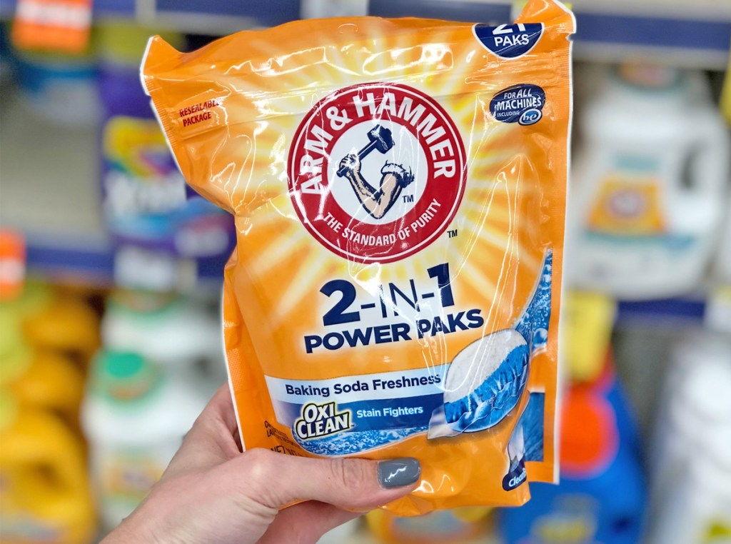 person holding up an orange bag of arm & hammer laundry detergent pods