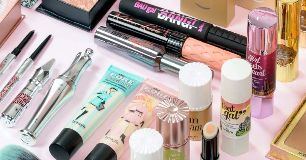 benefit primers, mascaras, and highlighters laying on a pink background