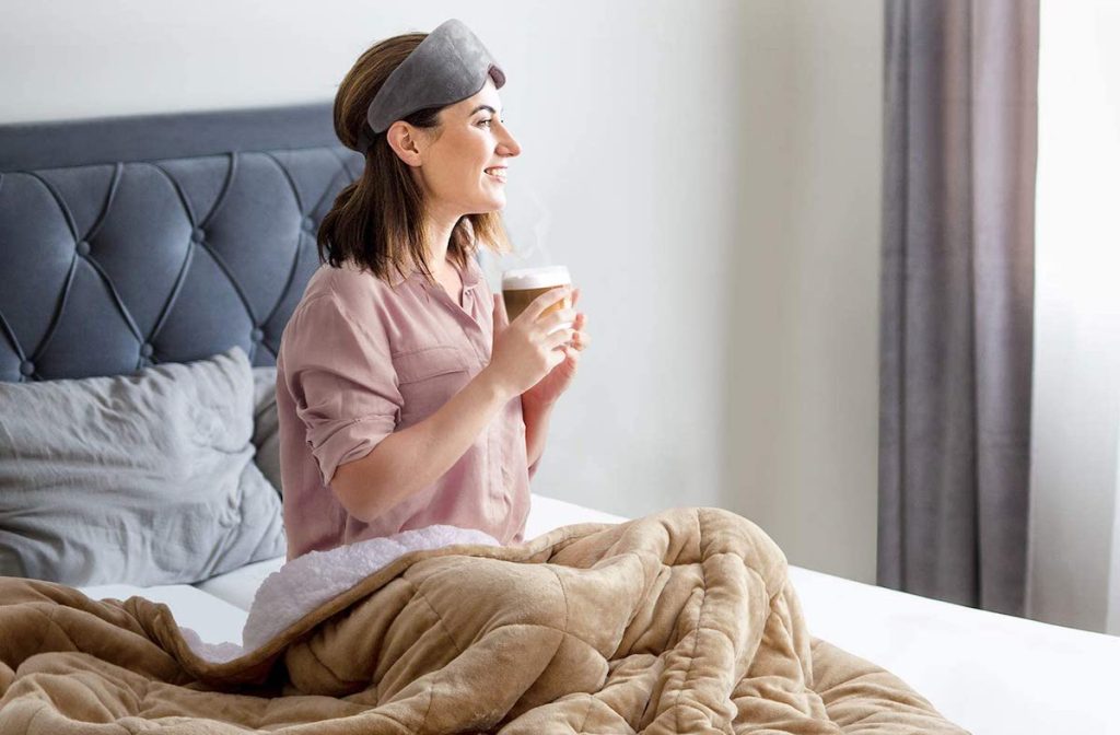 woman sitting on a bed holding a coffee