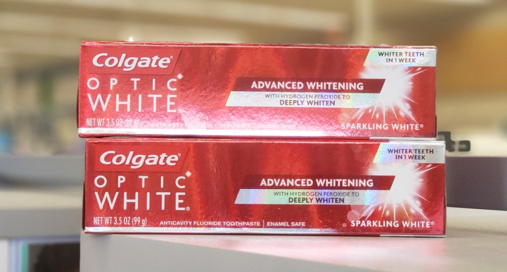 two red boxed of colgate optic white toothpaste stacked on one another