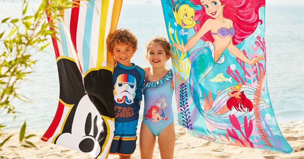 two children on beach with Disney towels