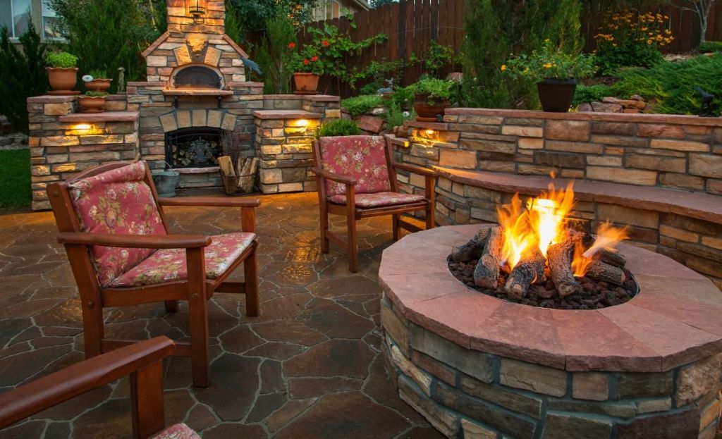 A fire burning outside on a patio next to chairs