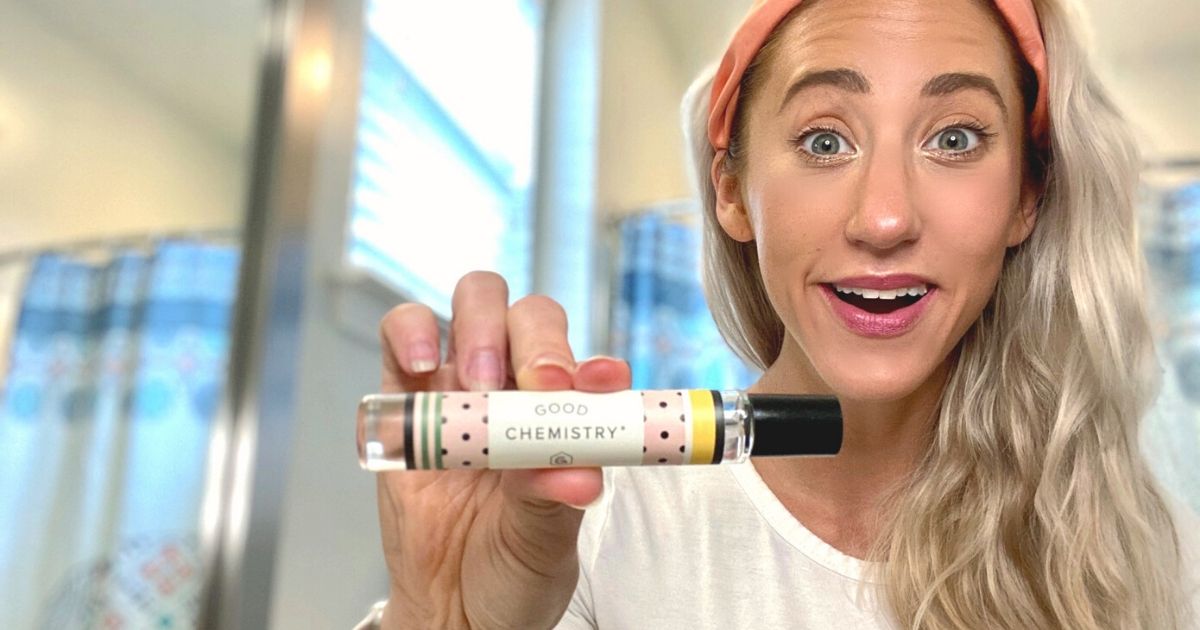 A woman holding a perfume rollerball in the bathroom