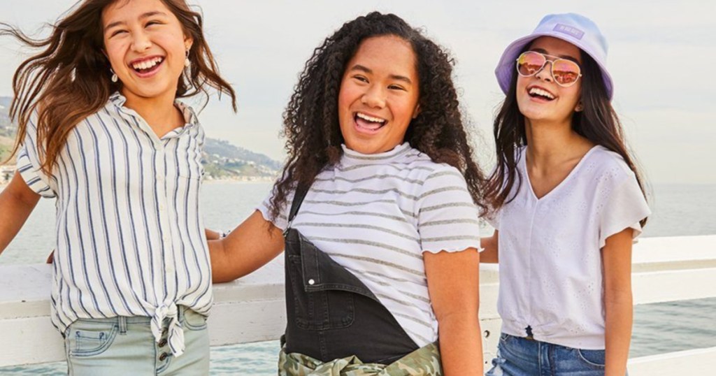 3 girls standing next to each other outside laughing