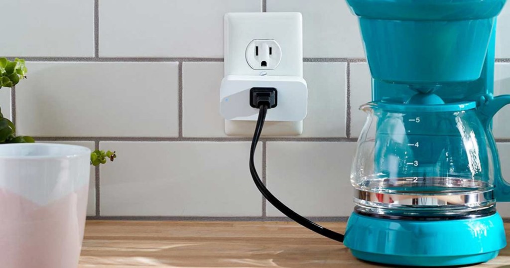 teal colored coffee pot plugged into a white smart plug on white tile backsplash