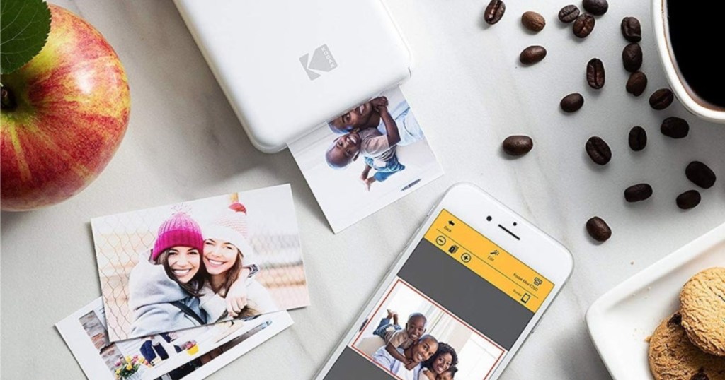 cell phone, photos, white photo printer, coffee, apple, and cookies on white table