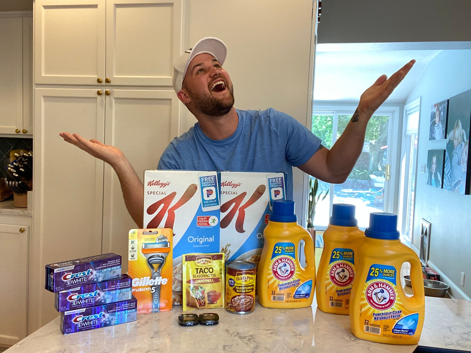 Man standing behind a table full of household items with hands raised in surprise