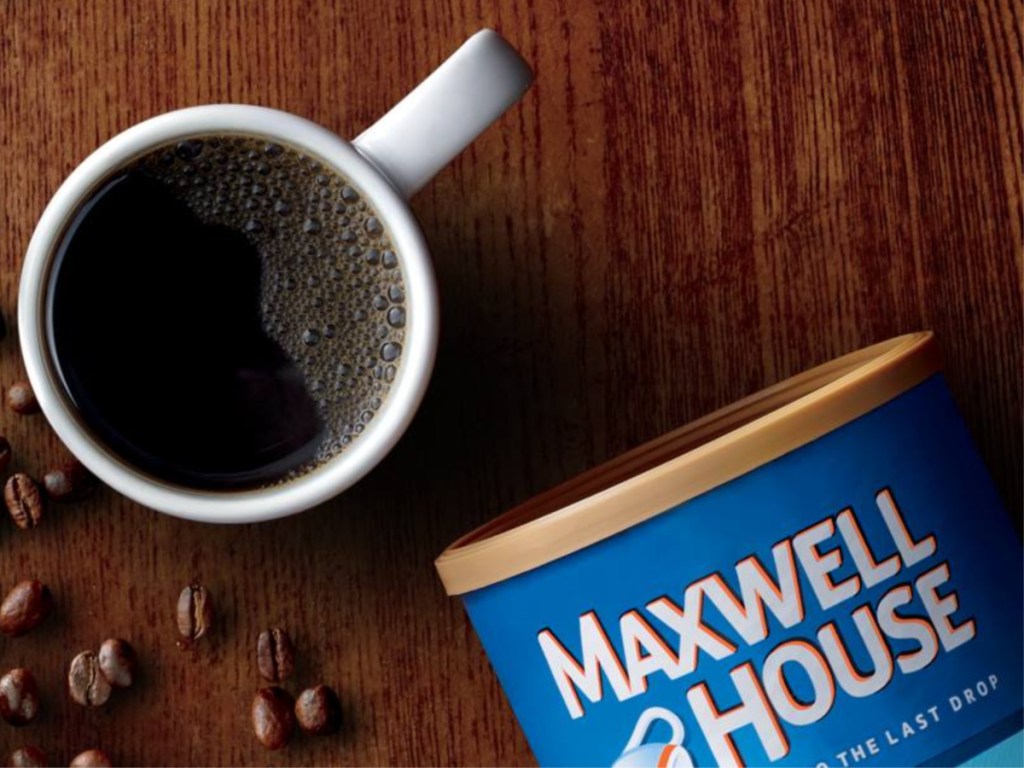 cup of coffee, coffee beans, and blue tin of coffee on wood table