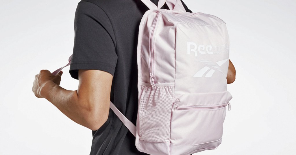 person in black shirt wearing a light pink reebok backpack