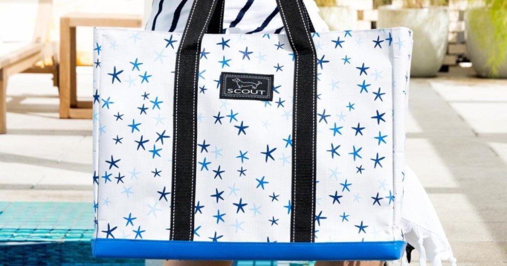 woman holding white and blue star patterned tote bag at pool