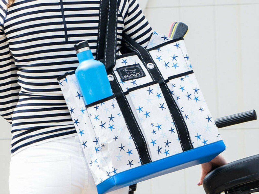 woman carrying white and blue star patterned tote bag over shoulder