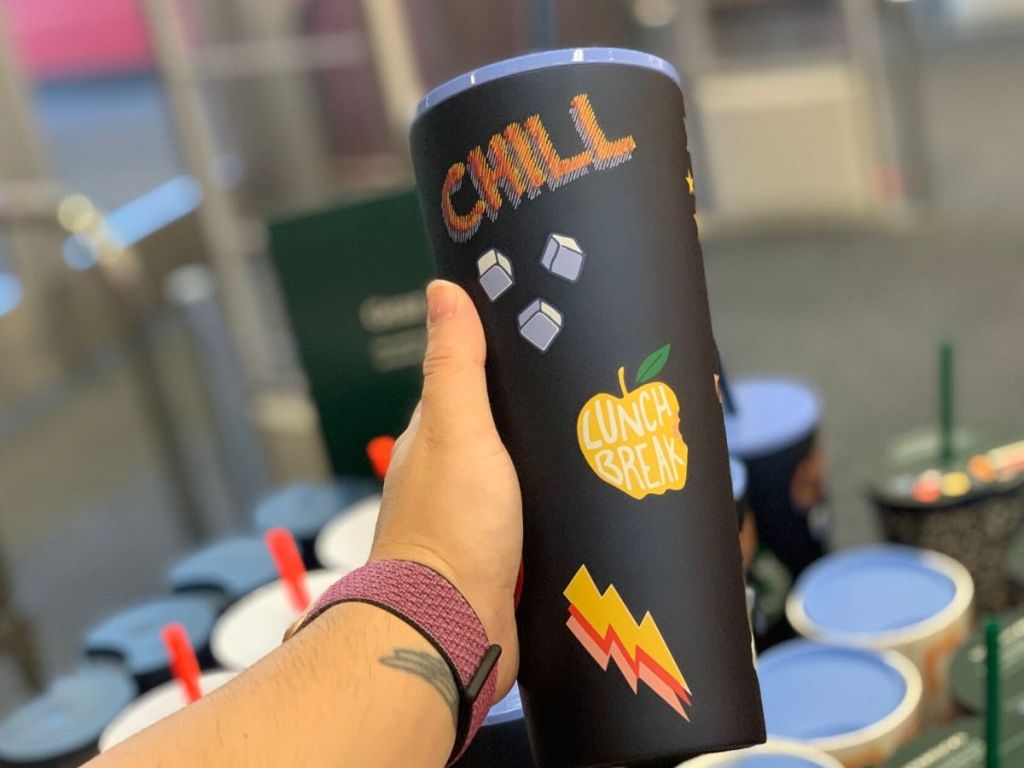 woman's hand holding tall cup with lid and straw