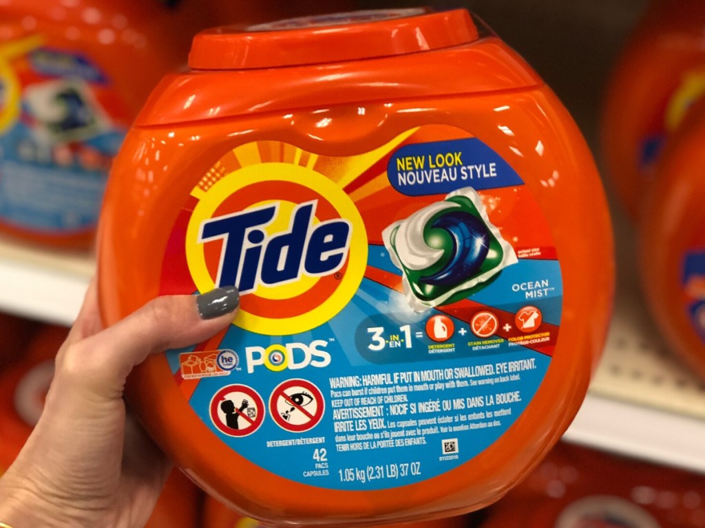 hand holding a large container of Tide Pods