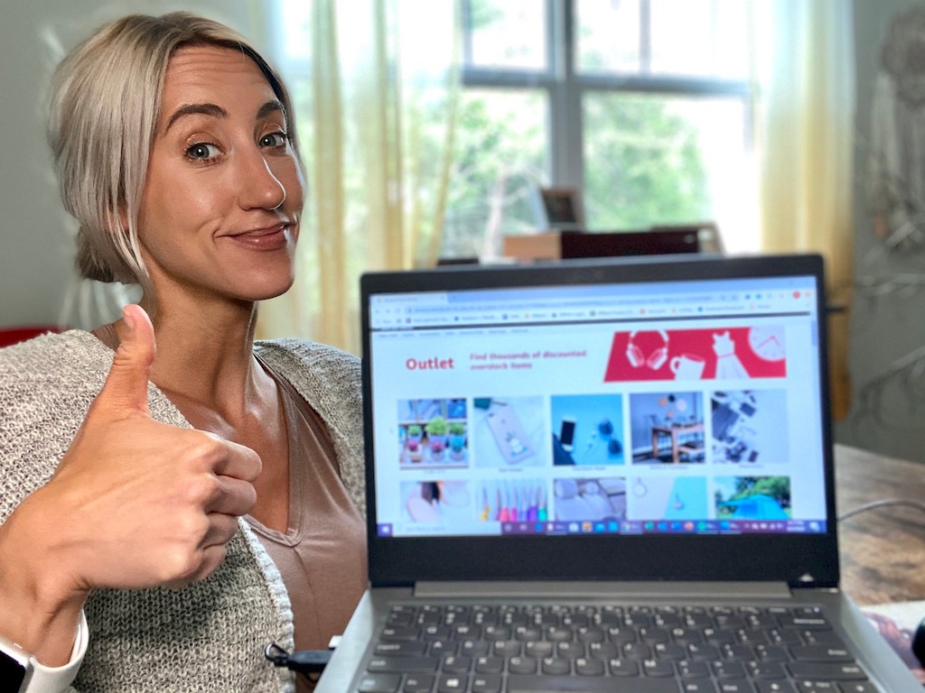 woman holding onlineputer with Amazon outlet on screen and doing a thumbs up