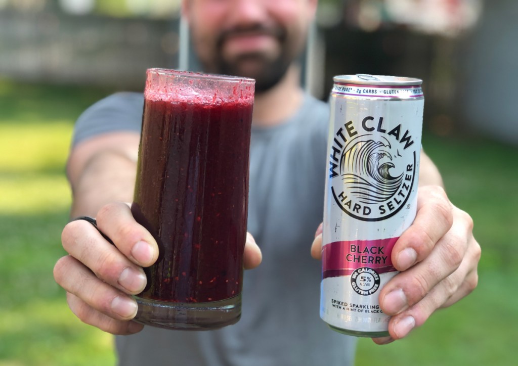 man holding up can of white claw and slushie