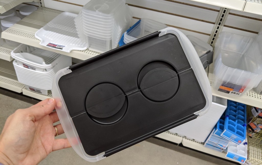 hand holding a black and clear storage bin