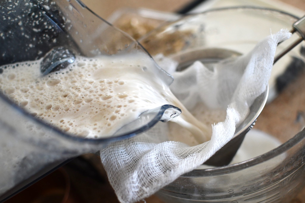 pouring oat milk into the strainer