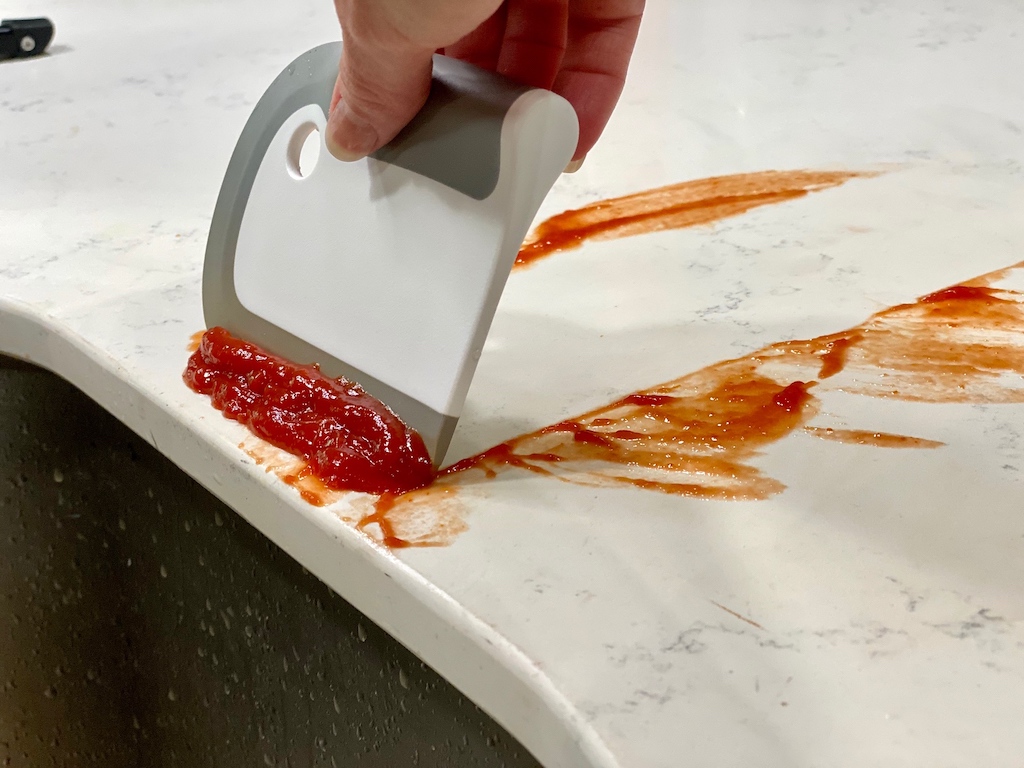 scraping ketchup off counter with dish squeegee