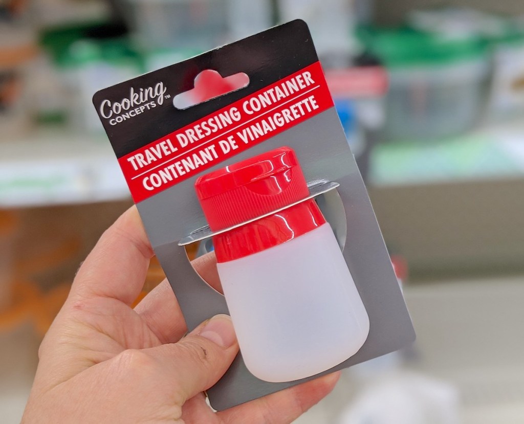 hand holding a clear and red silicone dressing bottle