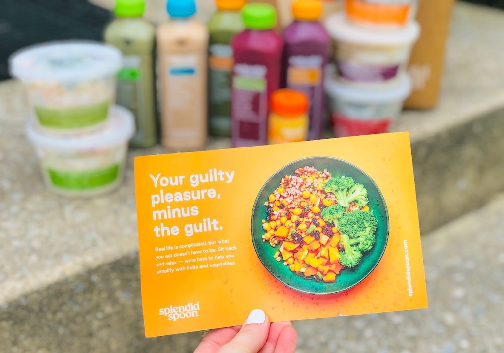 hand holding an orange flyer with food in background