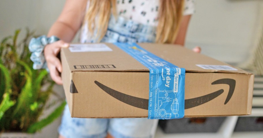 woman holding out an amazon box with blue printed packaging tape on it