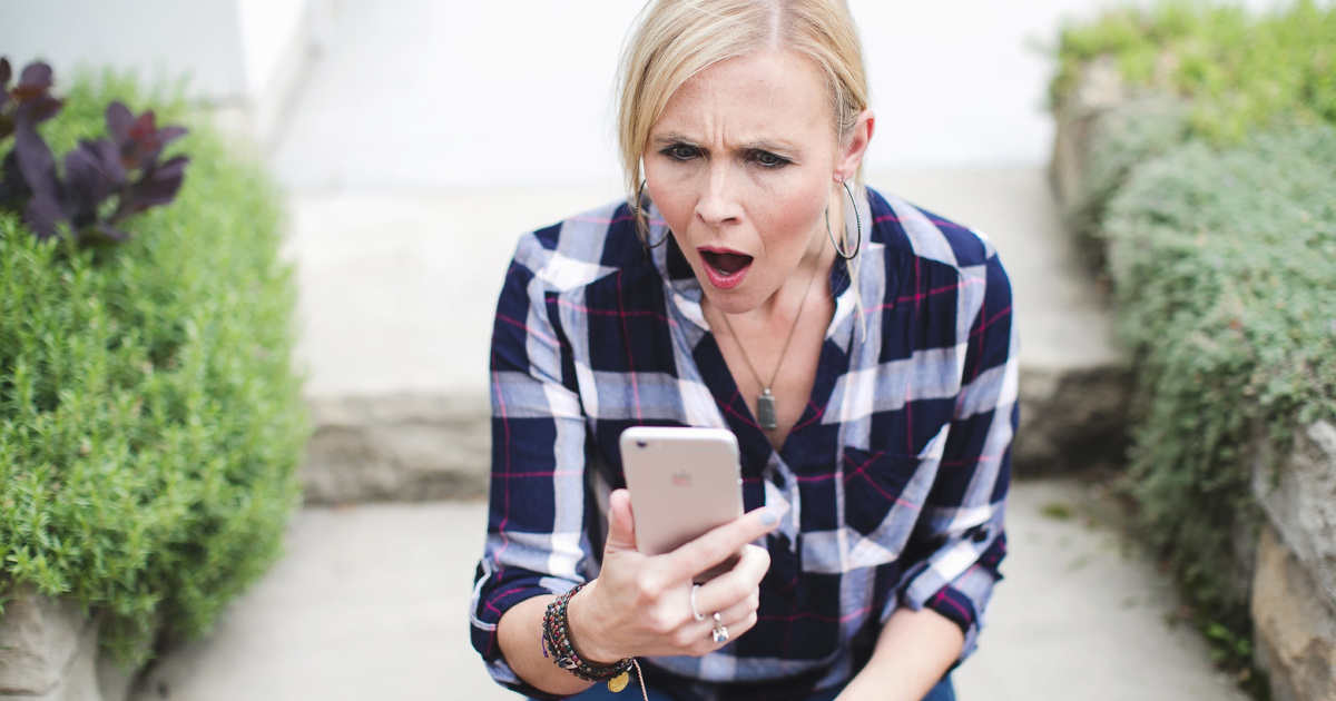 woman sitting outside looking at iPhone