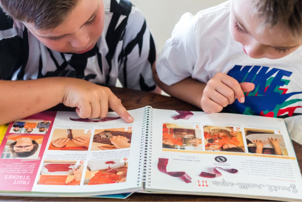 2 boys reading directions in cookbook