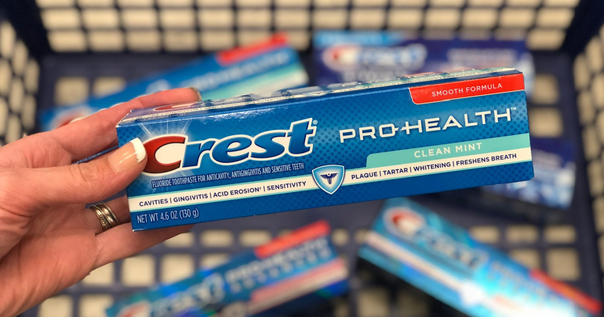 manicured hand holding toothpaste above cart full of toothpaste in store