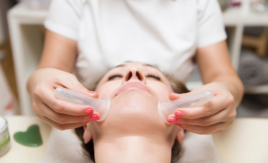 A woman having facial cupping done at a spa