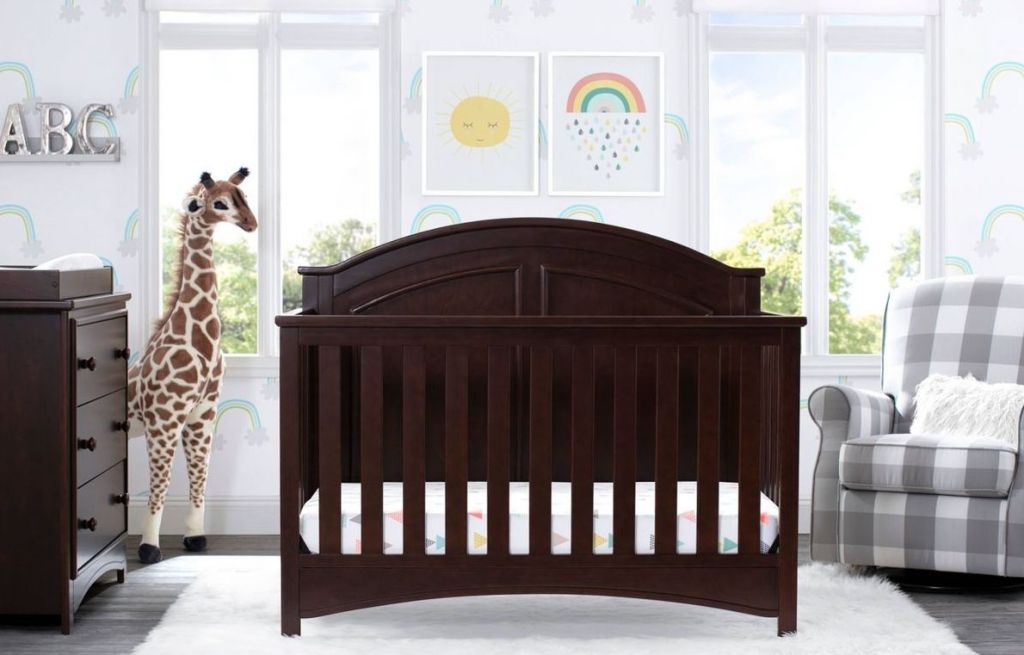 nursery with large giraffe, crib, chair and dresser