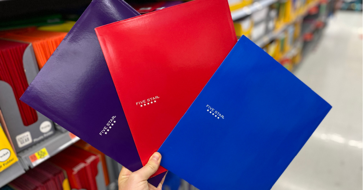 hand holding purple, red, and blue folders in store aisle