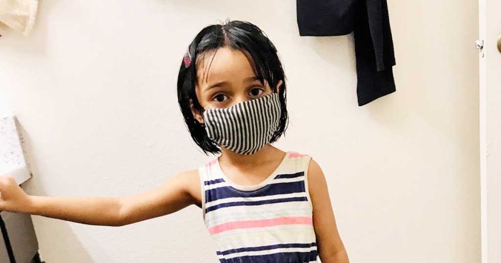 girl in striped dress wearing a black and white striped face mask