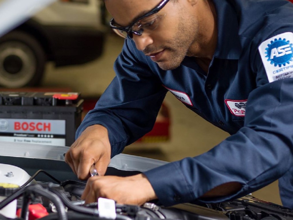 man leaning into the engine of a car