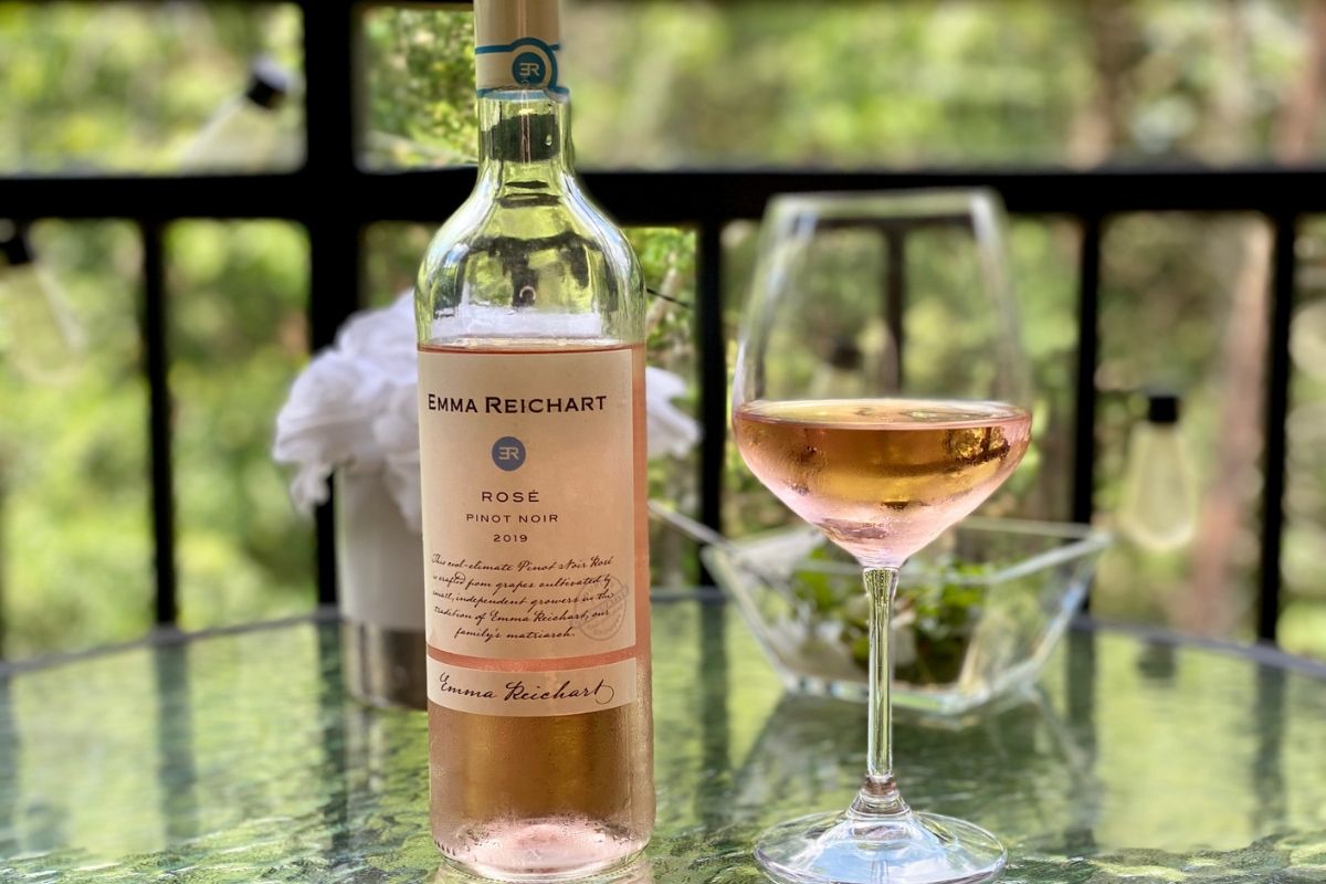 A bottle of rosé next to a wine glass on a table