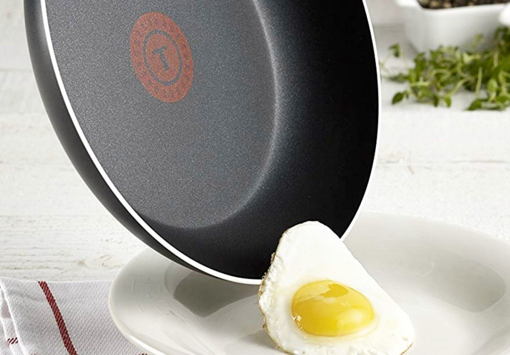 black frying pan with egg sliding out of it onto plate