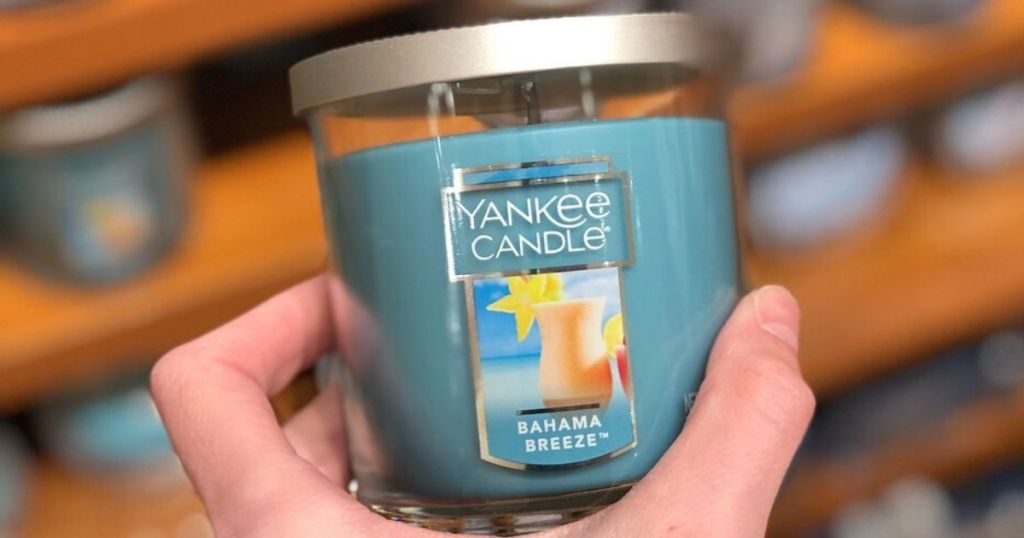 woman's hand holding a small jar candle 