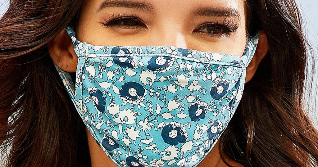 woman with dark brown hair wearing a light blue face mask with floral pattern on it