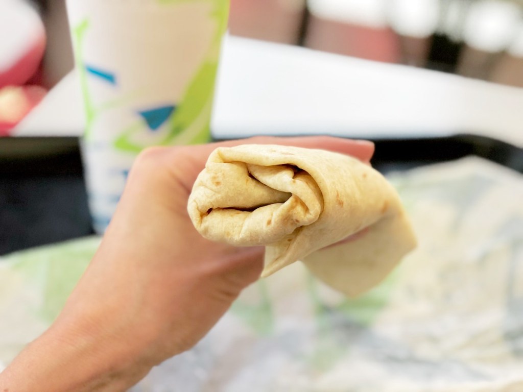 hand holding burrito up to take a bite