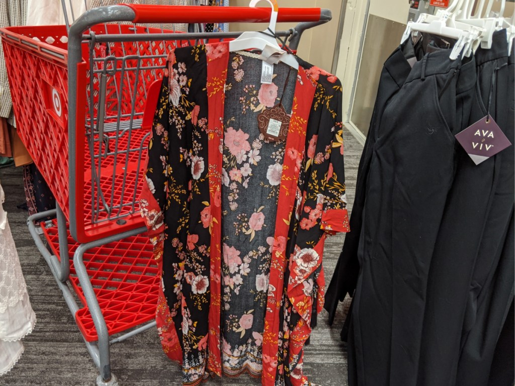 red grocery cart with woman's shirt hanging on it in store