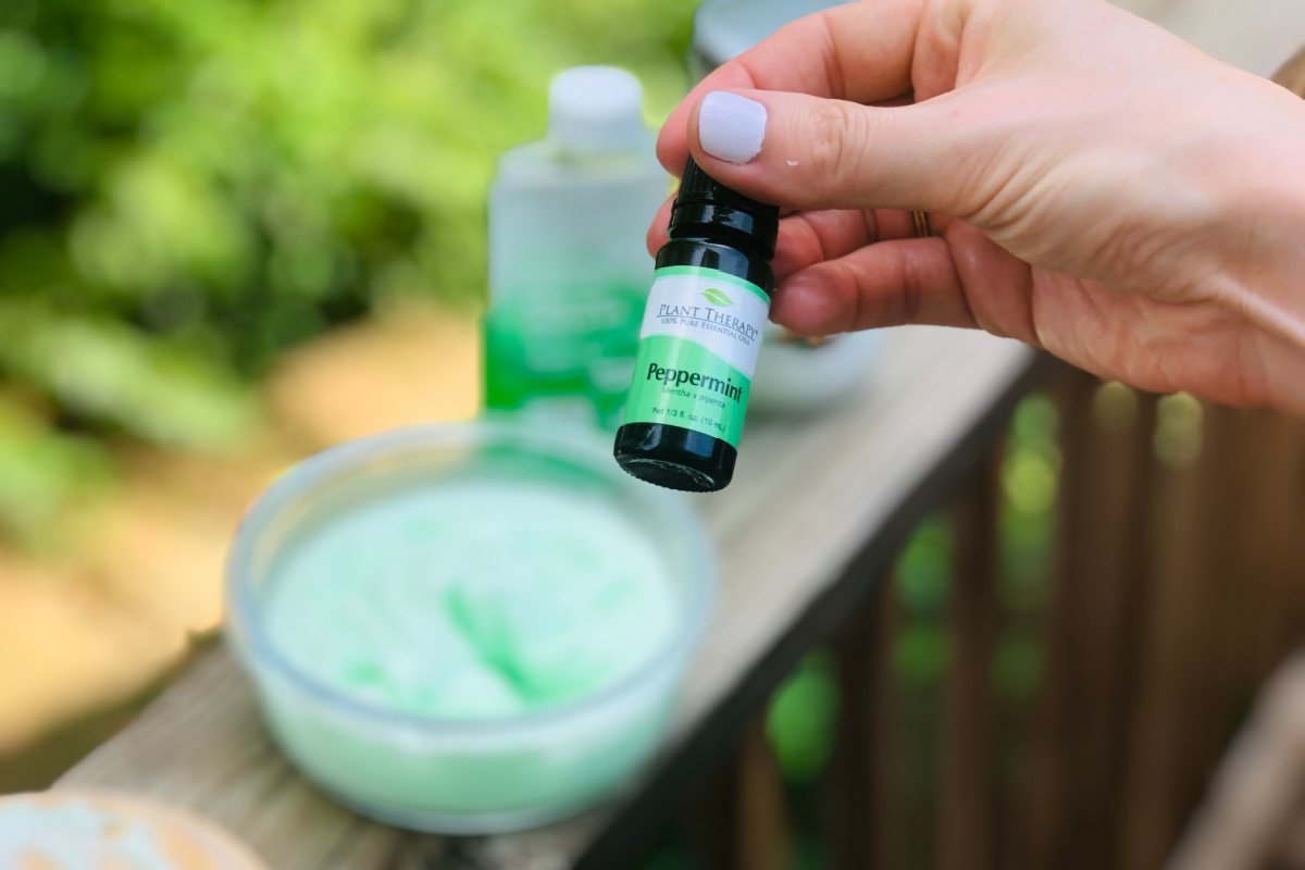 hand holding a small amber bottle of peppermint essential oil