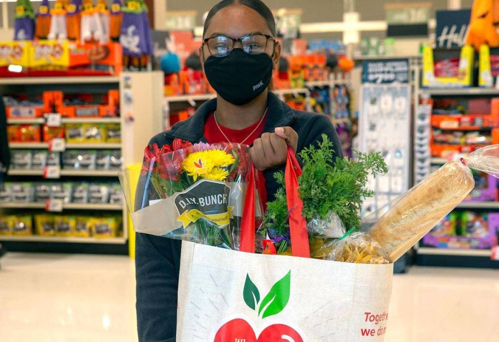 woman holding up bag of groceries in store