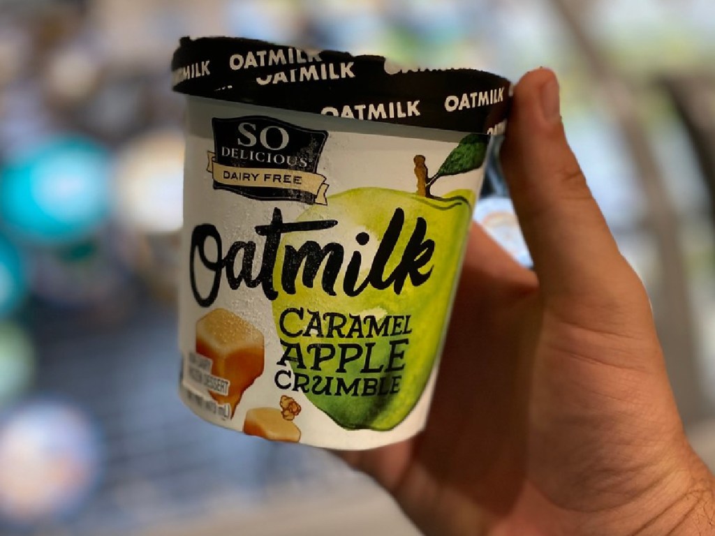 hand holding pint of ice cream up by store display