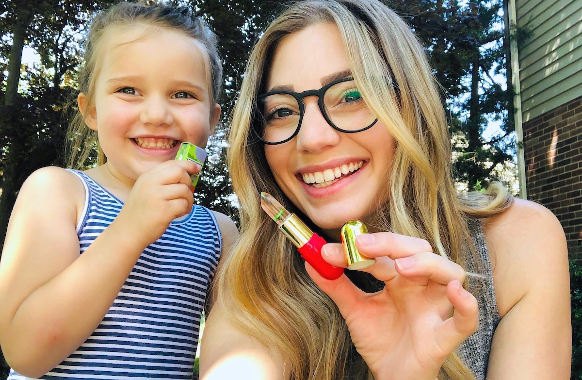 woman and girl holding up lip balm smiling