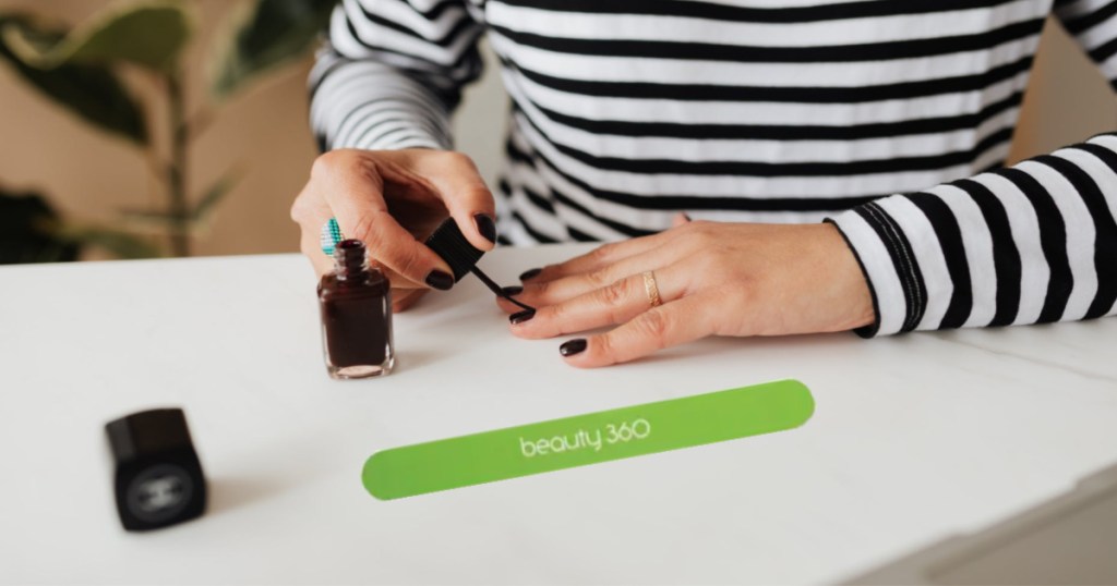 woman painting nails with emery board on table