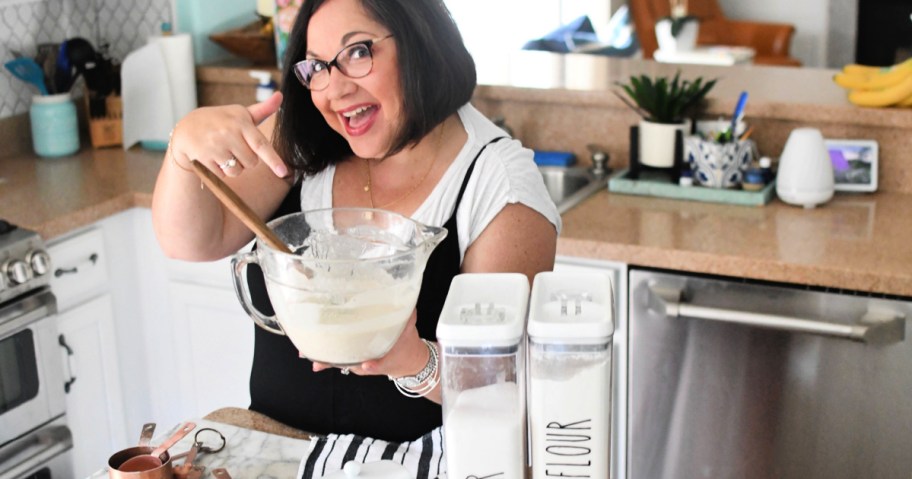 woman holding up glass bowl pitcher filled with batter